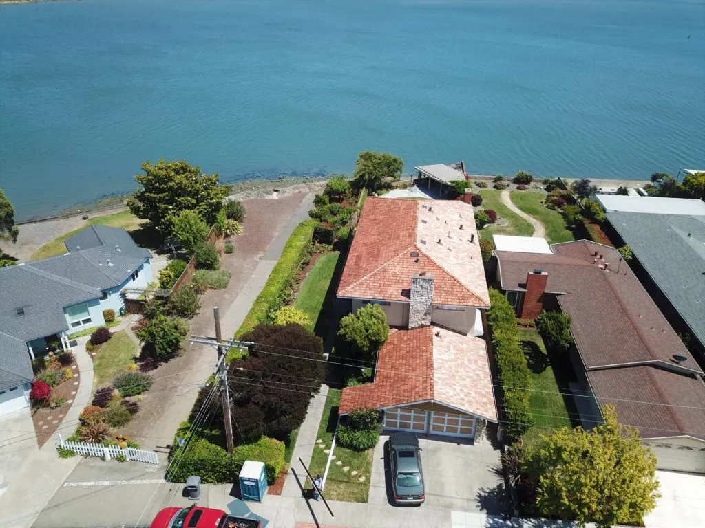 Aerial view of a coastal residential area with houses featuring well-maintained roofs, highlighting work possibly done by PRI-Premiere Roofing Inc. in Livermore.